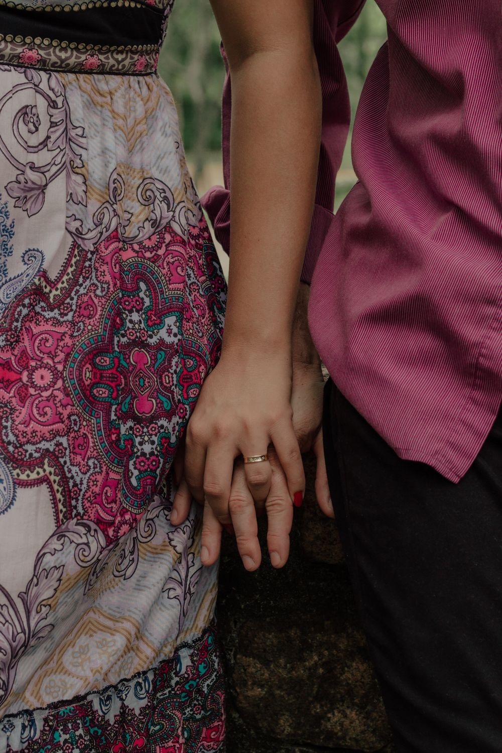 Close-up of a couple holding hands, focusing on a wedding ring, symbolizing love and commitment.