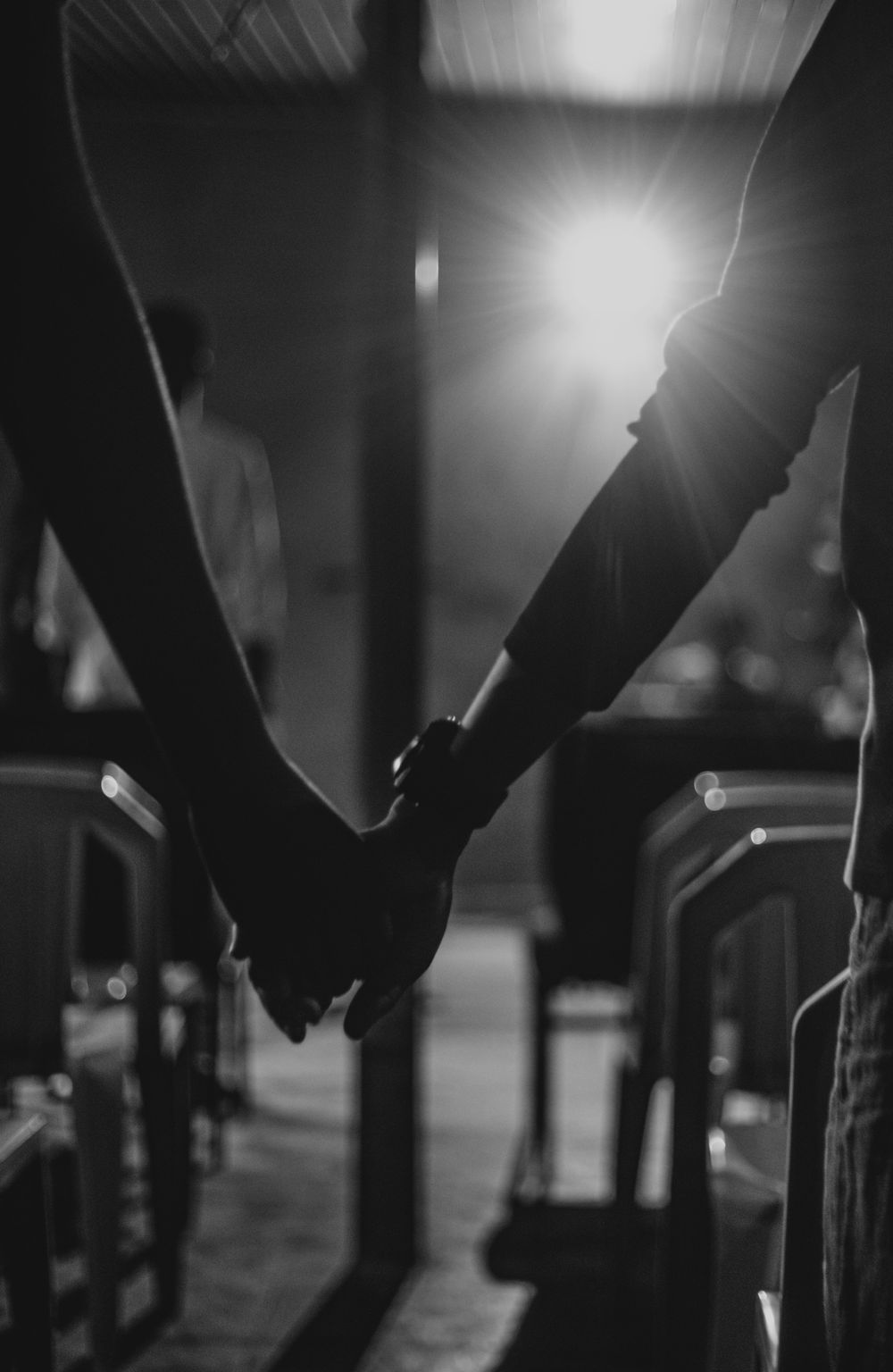 Silhouetted couple holding hands, creating a romantic atmosphere in black and white.