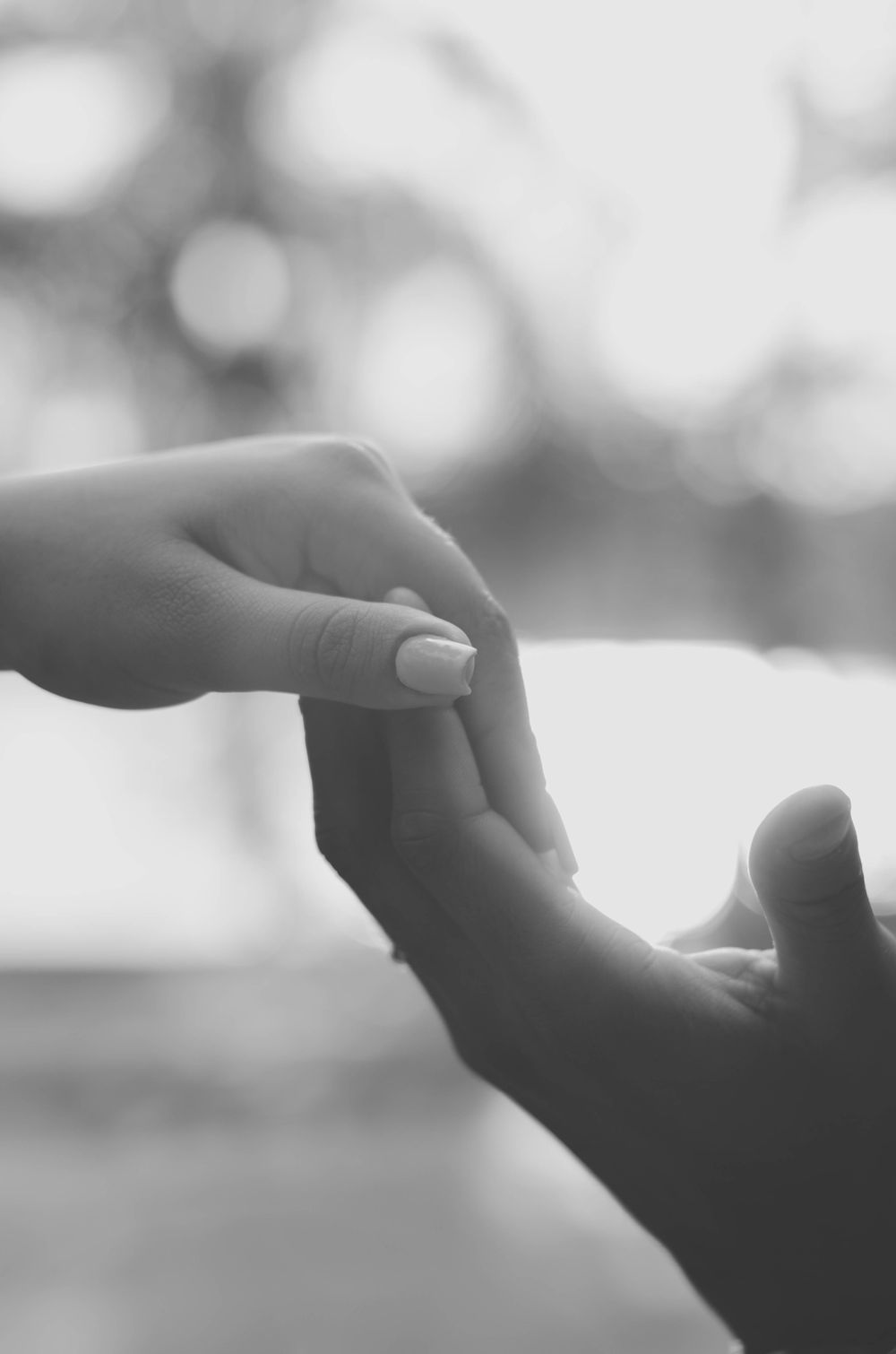 Artistic black and white close-up of two hands gently touching, conveying love and connection.