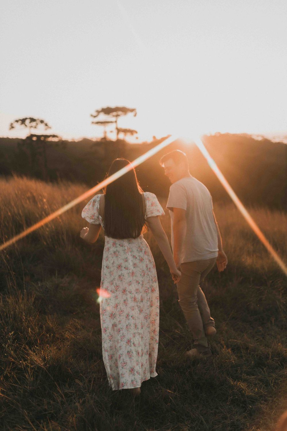 A young couple enjoying a romantic walk at sunset in a summer field, capturing love and serenity.