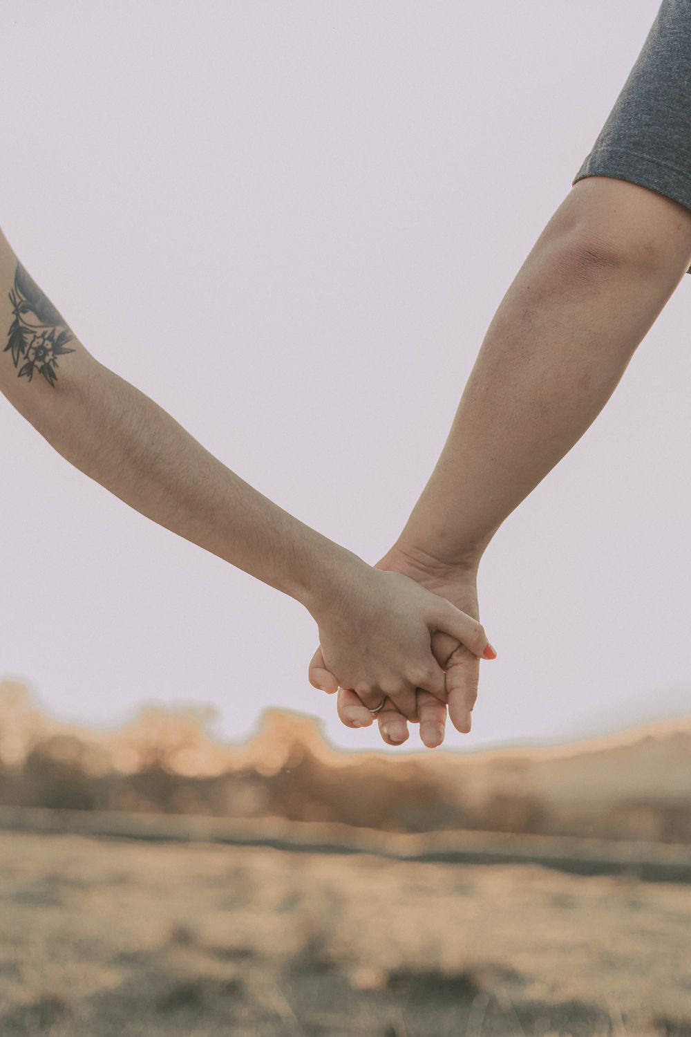 Two people holding hands outdoors, symbolizing love and connection.