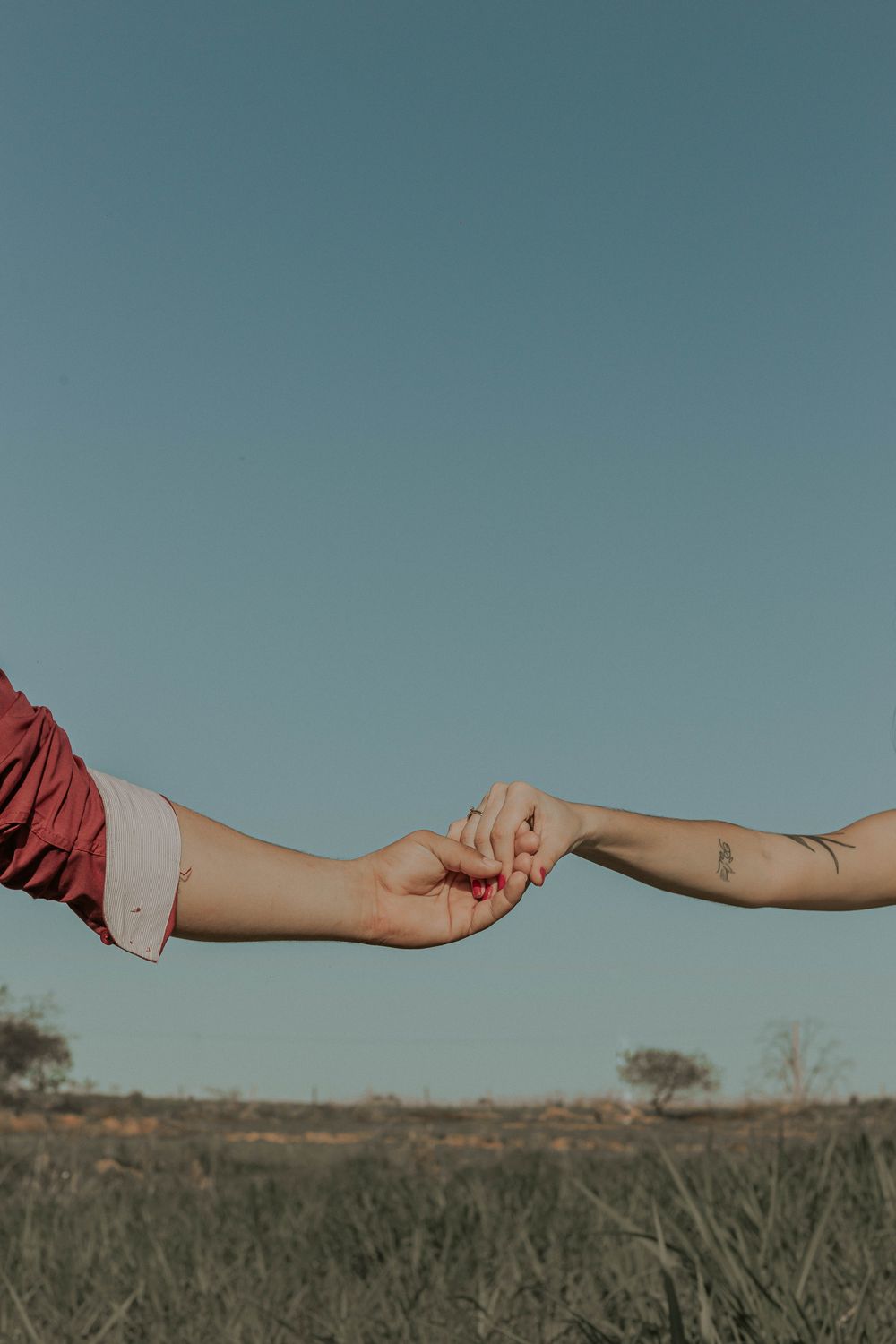 A couple holds hands in a serene outdoor setting in Presidente Prudente, Brazil.