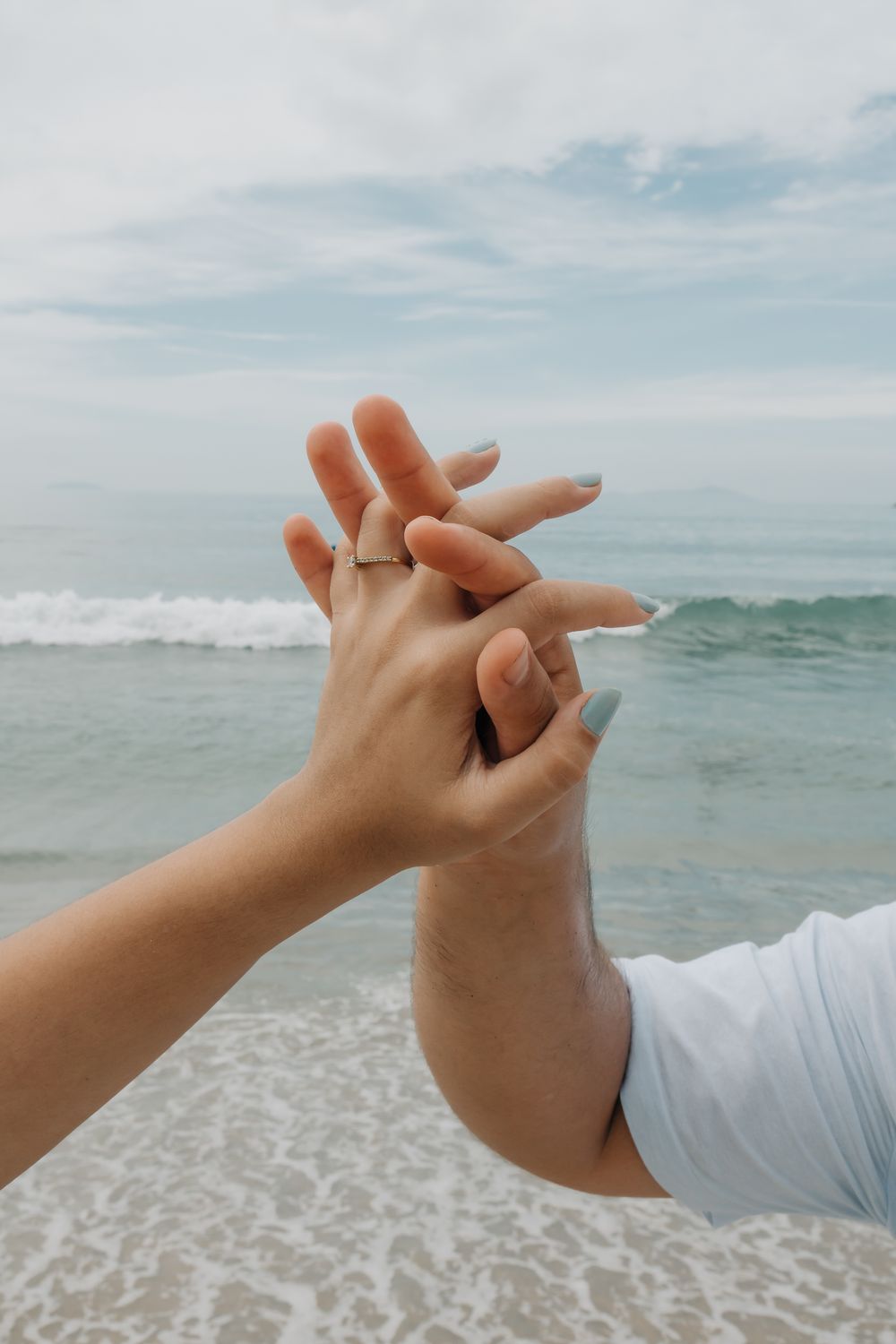 Close-up of a couple holding hands by the ocean at Ubatuba Beach, São Paulo.