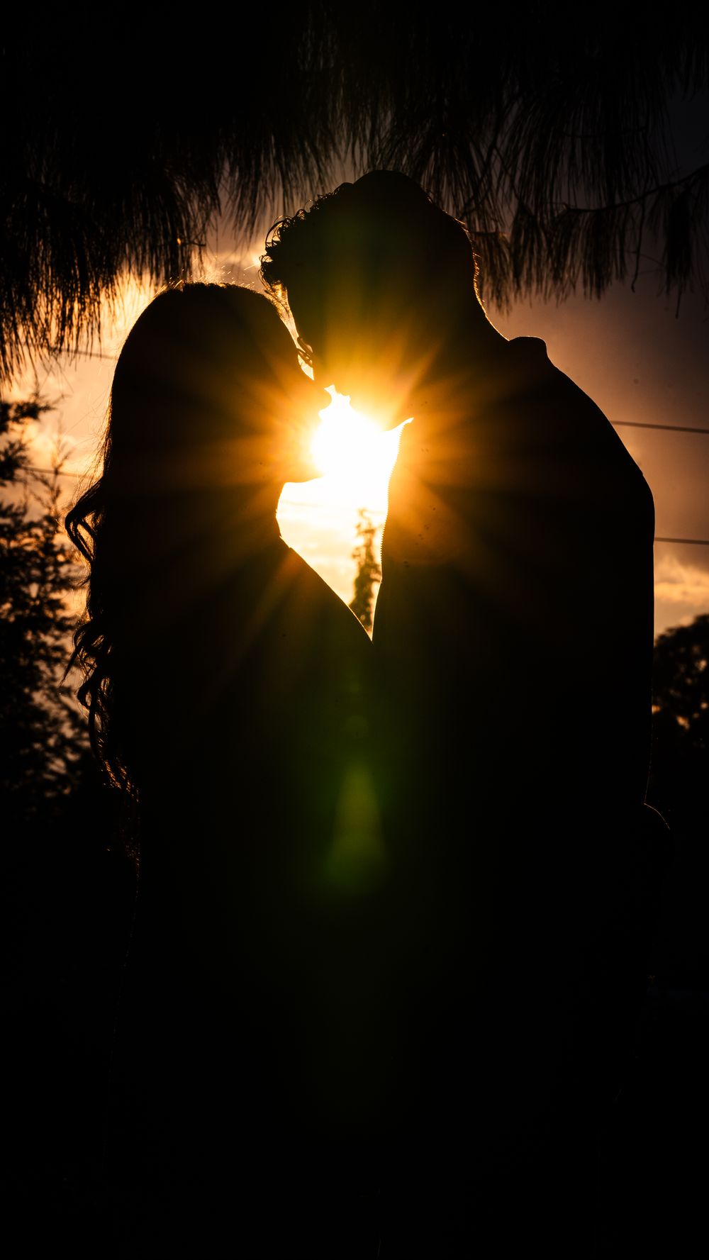 A couple sharing a romantic moment silhouetted by the sunset glow.