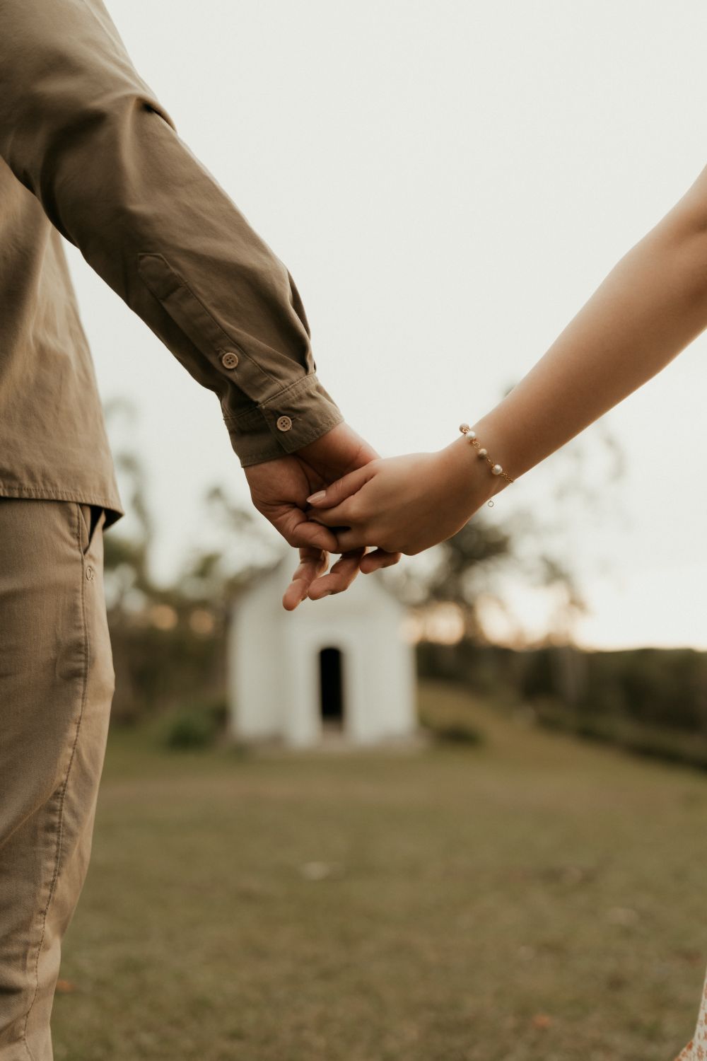 A tender moment of a couple holding hands in a serene outdoor setting.