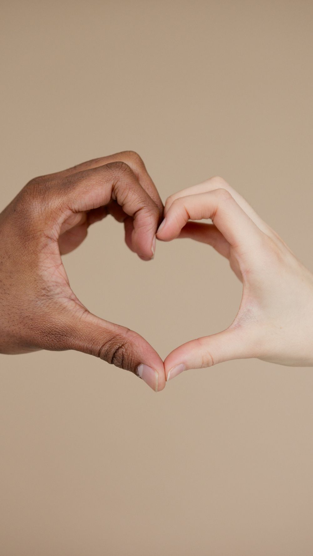 Two hands of different ethnicities form a heart shape, symbolizing unity and diversity.
