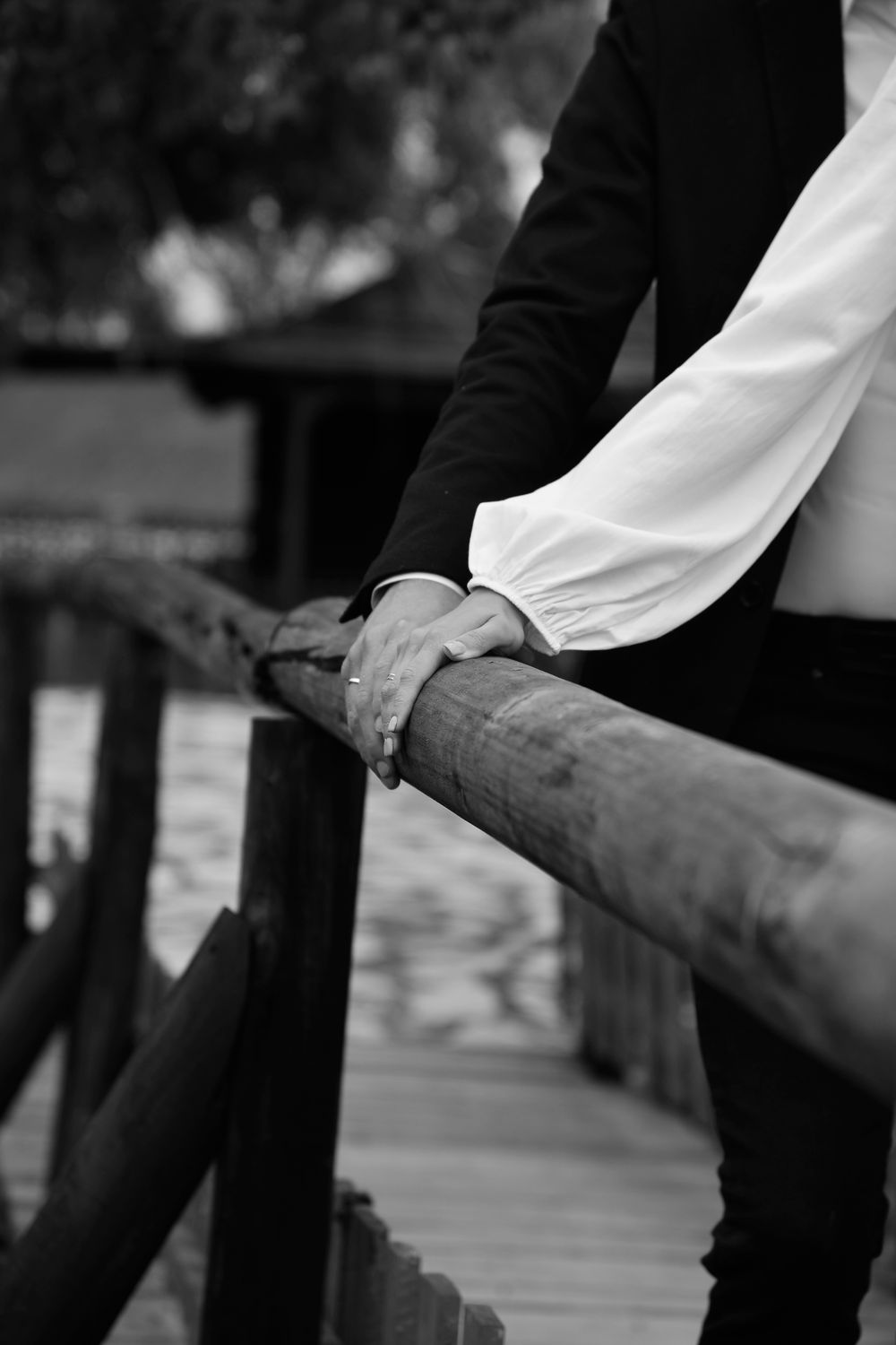 Artistic black-and-white photo featuring hands elegantly resting on a wooden railing, conveying a sense of tranquility.